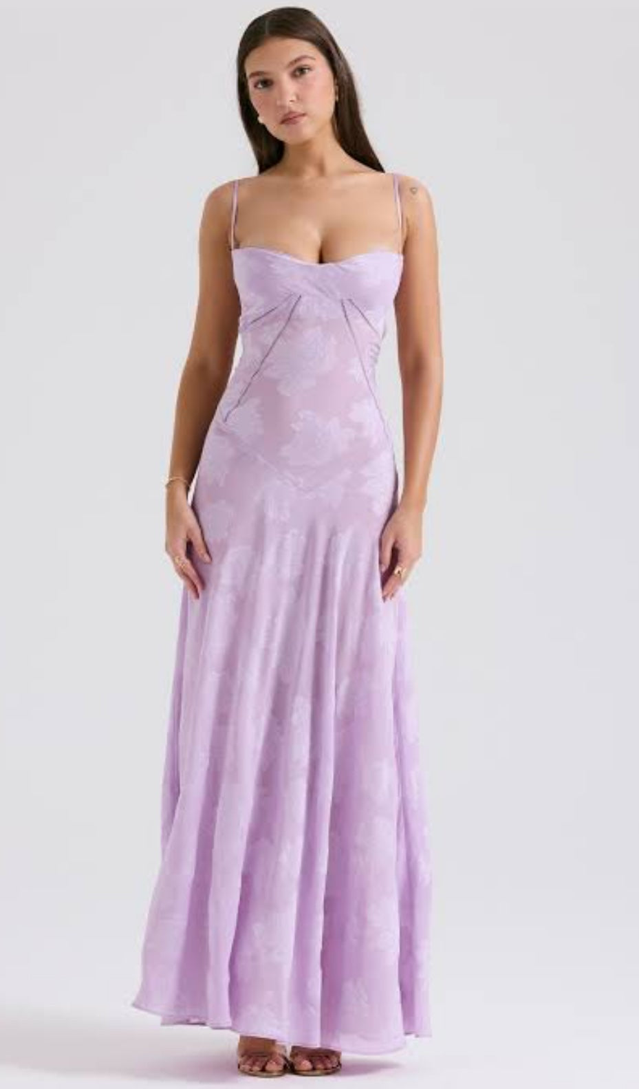 House of CB Seren Dress in Orchid. Model stands against a white wall facing the camera directly wearing a lilac lace dress.