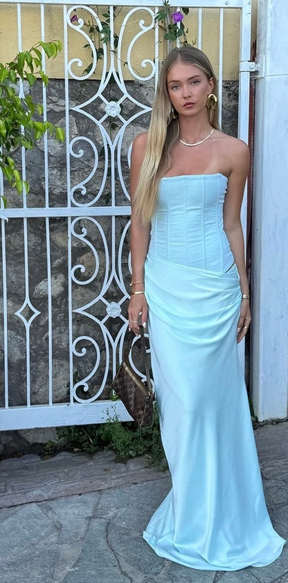 Woman in a light blue Hntr the Lable Huxley strapless gown standing in front of a decorative metal gate.