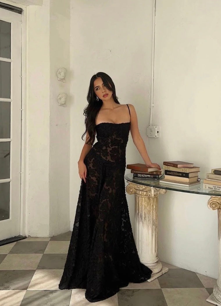House of CB Seren dress in black. Model stands on tiled floor leaning on a marble  hall table