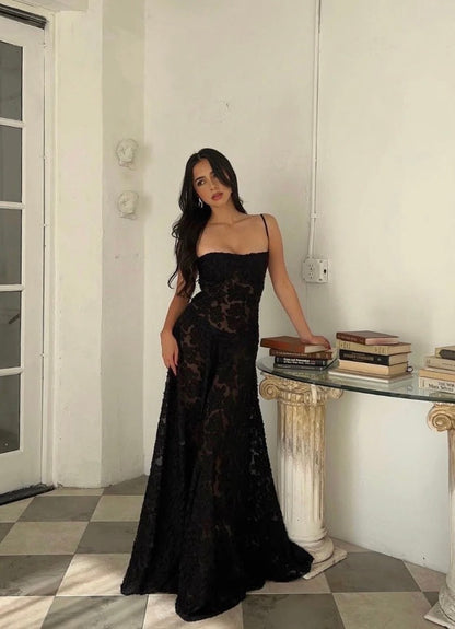 House of CB Seren dress in black. Model stands on tiled floor leaning on a marble  hall table