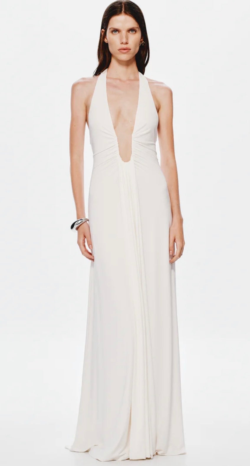 Woman wearing a white Misha Jennifer Cupro evening gown with a plunging neckline on a white background