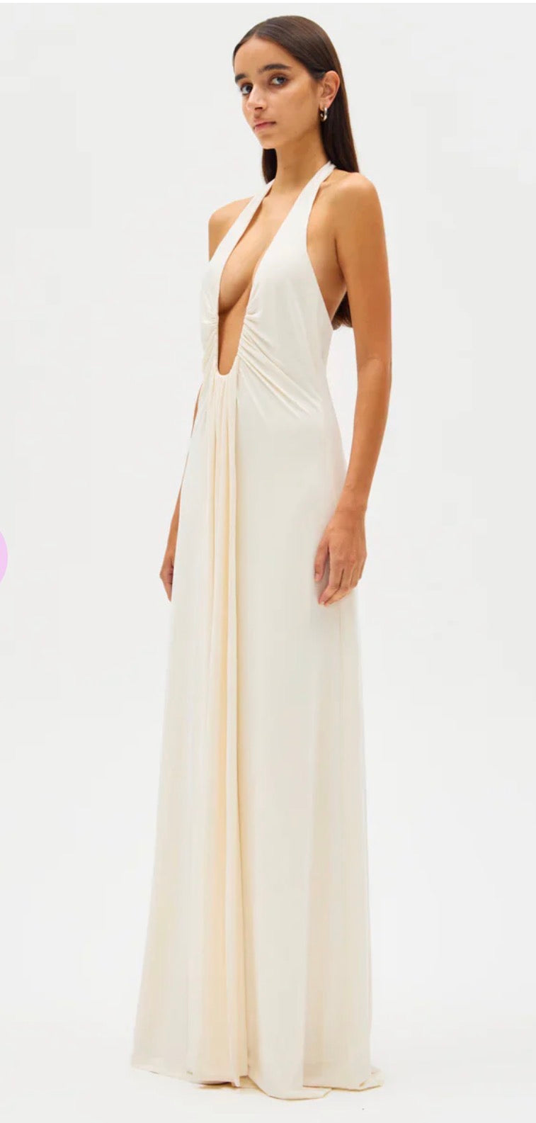 Woman wearing a white Misha Jennifer Cupro evening gown with a plunging neckline on a white background