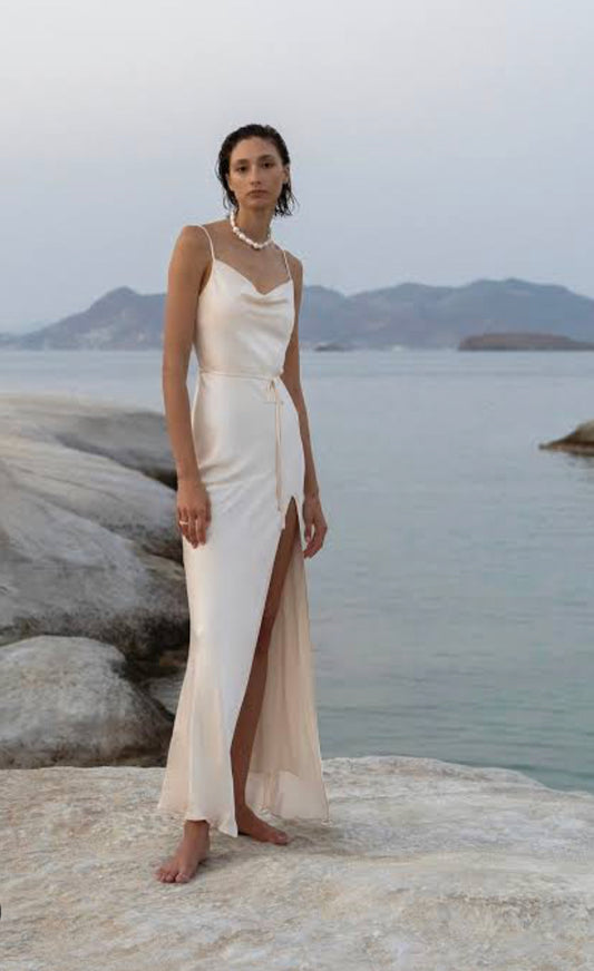 Shona Joy La Lune Cream Bias Cowl Maxi Dress model on rock with sea behind.