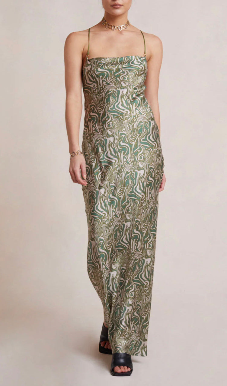Front view of Bec and Bridge green Alanis Silk Maxi Dress in signature swirl pattern with gold necklace and white/grey background.